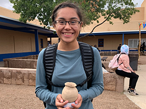 Smiling student holding up a ceramic pot