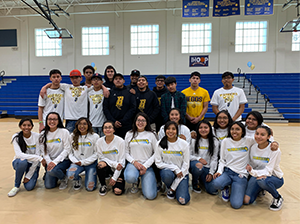 Students wearing Warrior t-shirts posing together in a gym